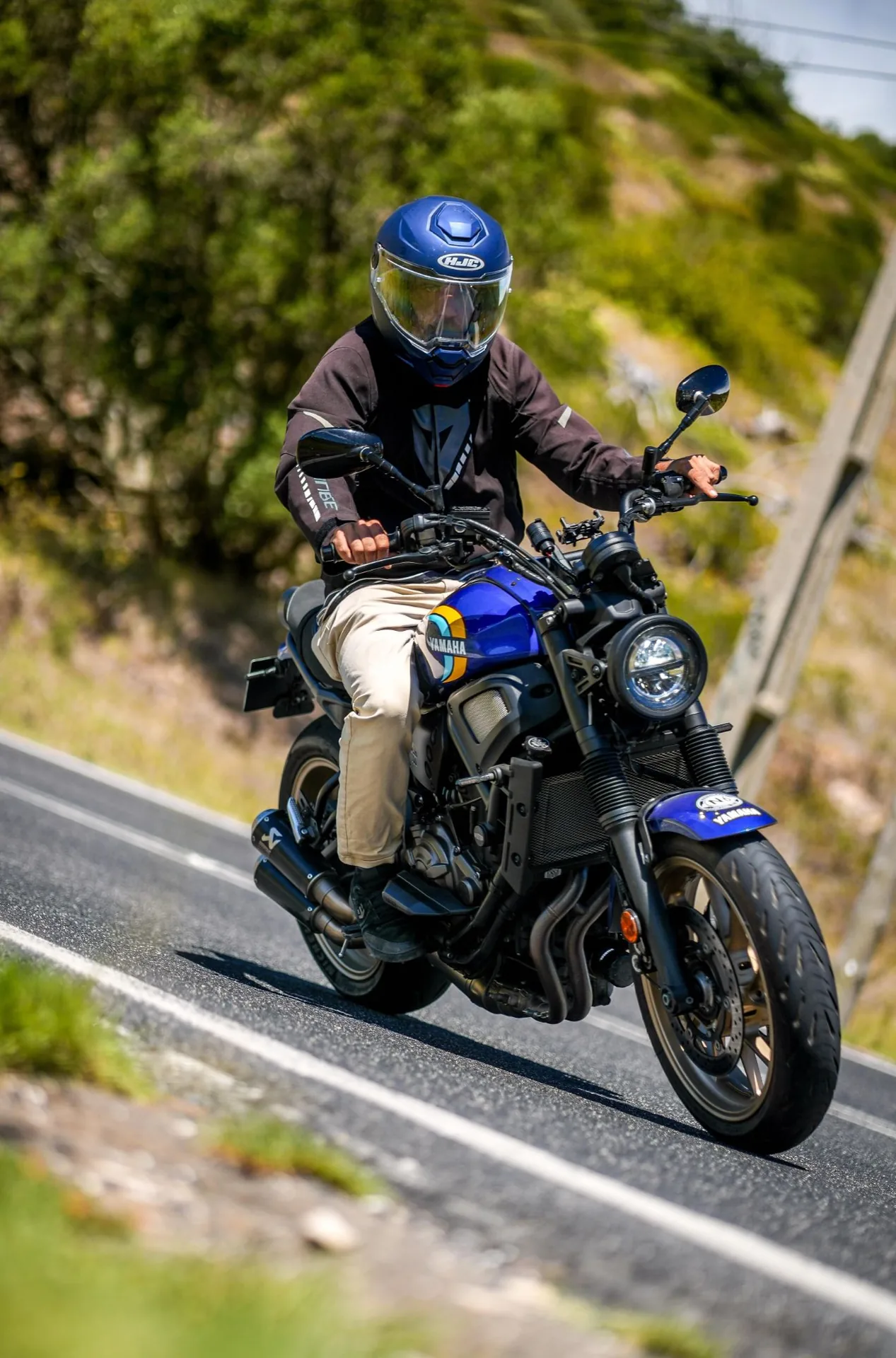 Motociclista de capacete azul numa Yamaha XSR 700 azul, numa curva de estrada rodeada de vegetação